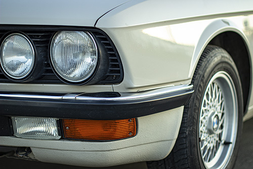 The closeup shot of the round headlights of a white vintage classic car